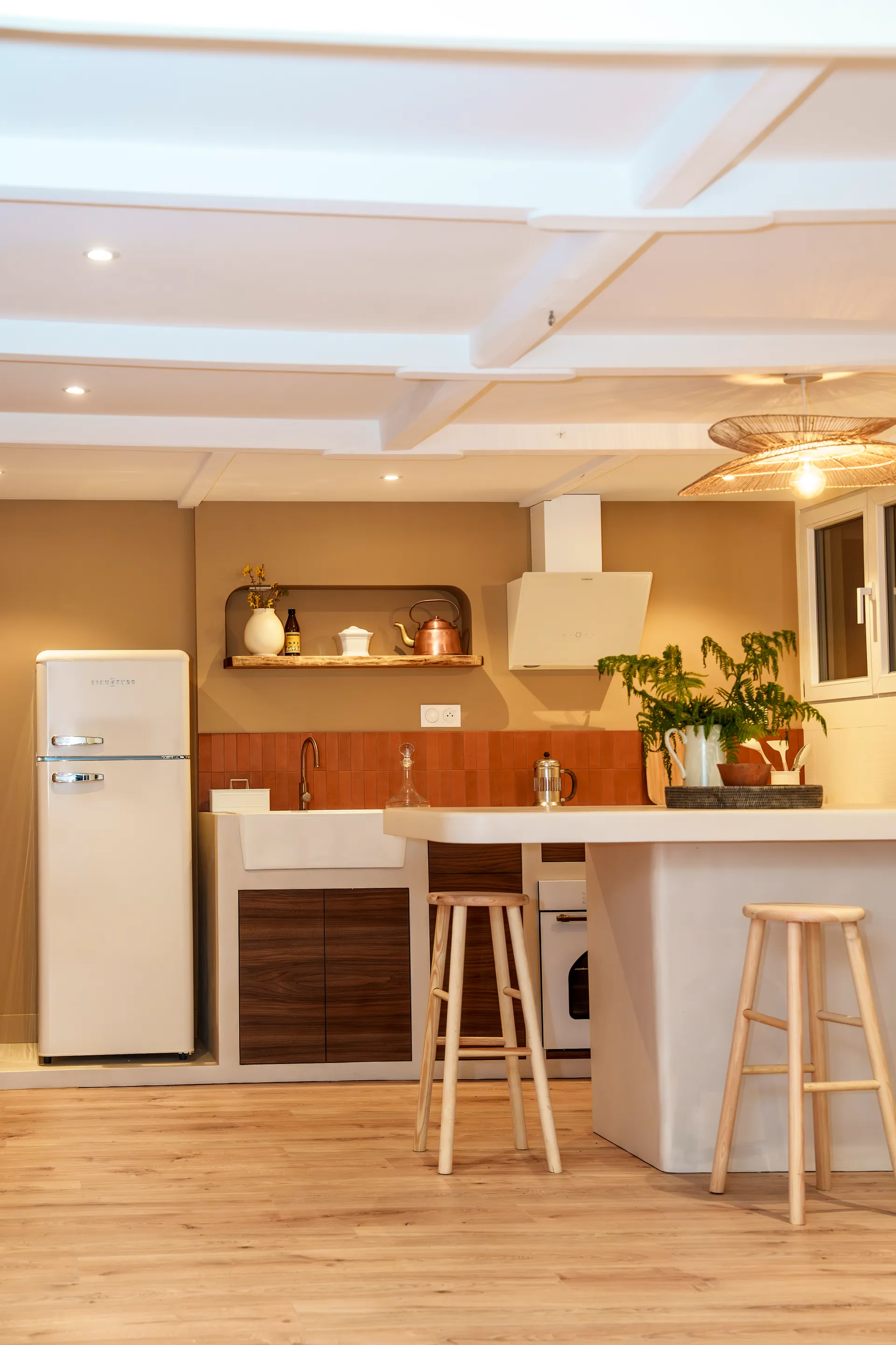Cuisine béton ciré avec bar, tabourets, îlot et luminaire suspendu — vue complète
