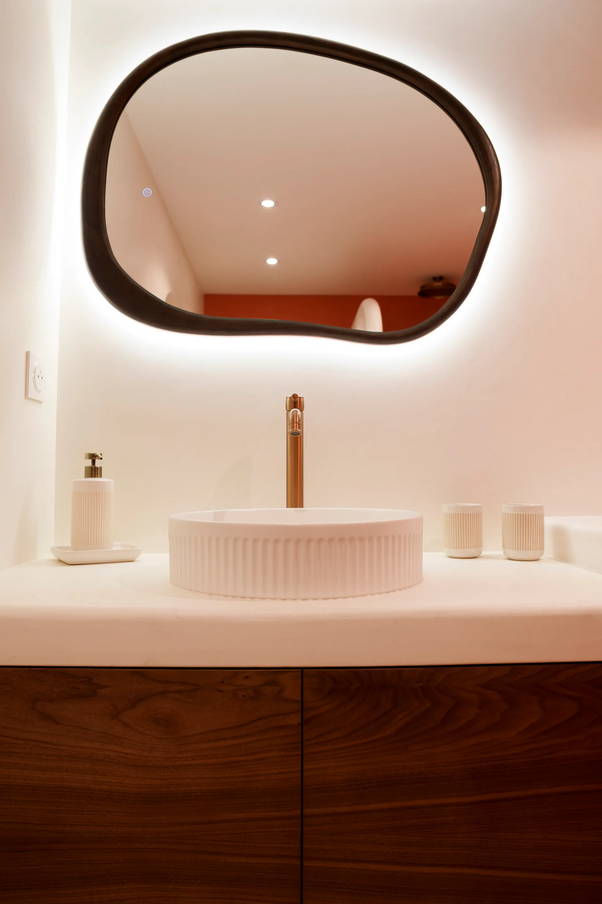 Meuble vasque béton ciré, miroir organique et robinetterie cuivre — réalisation DOD& Béton Ciré